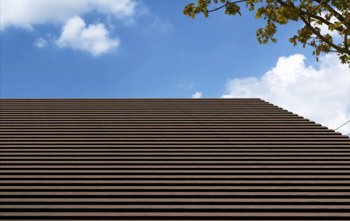 Lames brunes alignées en couverture de pergola sous un ciel bleu